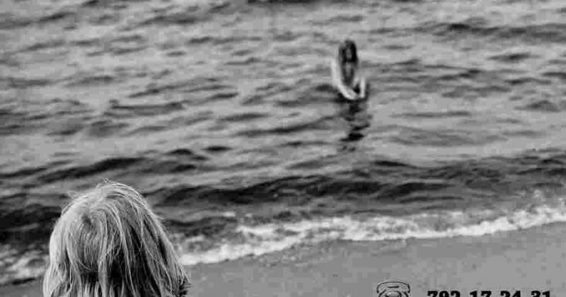 Dziecko na plaży i jedna osoba w wodzie